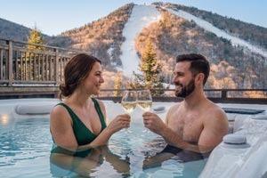 Couple sitting in hot tub with mountains in the background